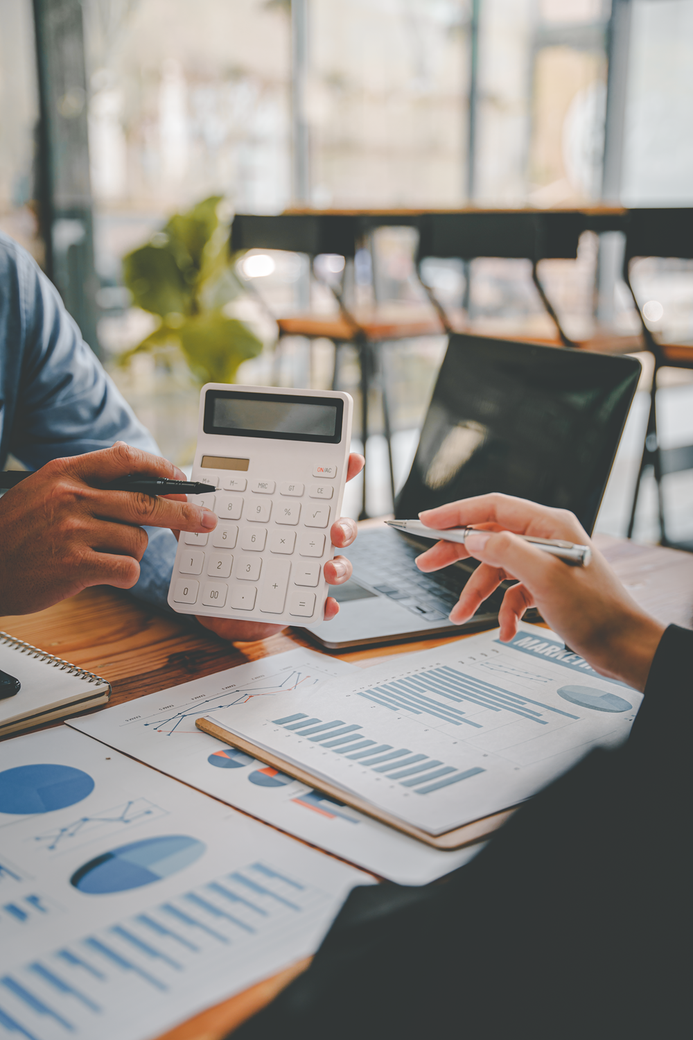 Business meeting analyzing charts with calculator discussion