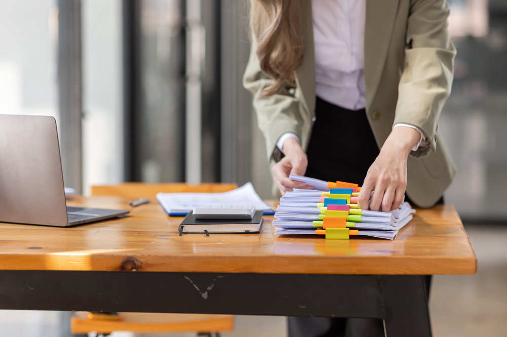 Person organizing documents on a wooden desk