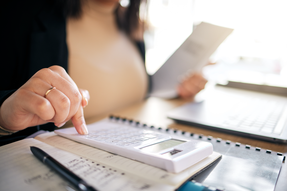 Person using calculator and reviewing financial documents