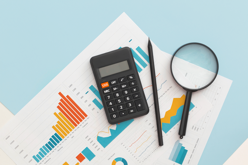Calculator and magnifying glass on financial charts.