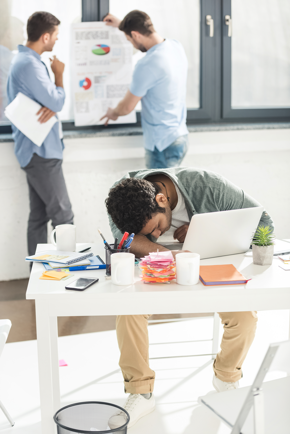 Office worker sleeping at desk during meeting.